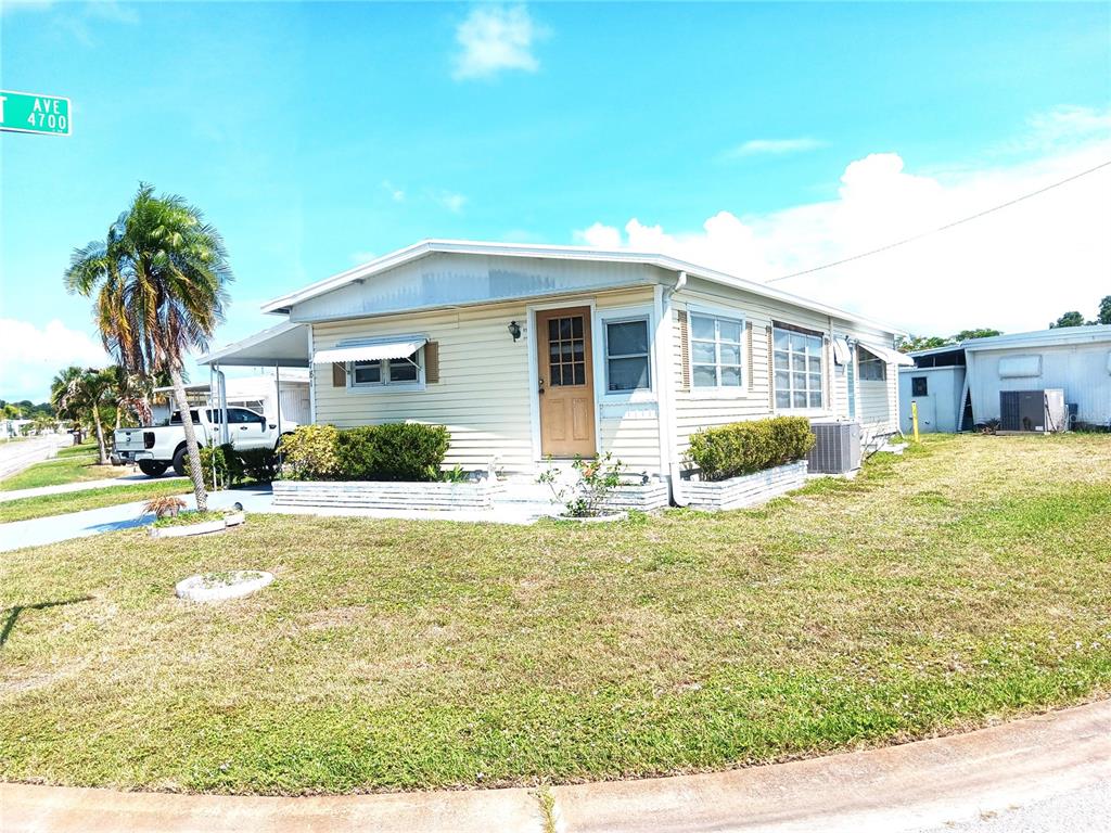 A single-story mobile home with light siding, a wooden door, and a palm tree — 1781 OLYMPIA FIELDS STREET, SARASOTA, FL