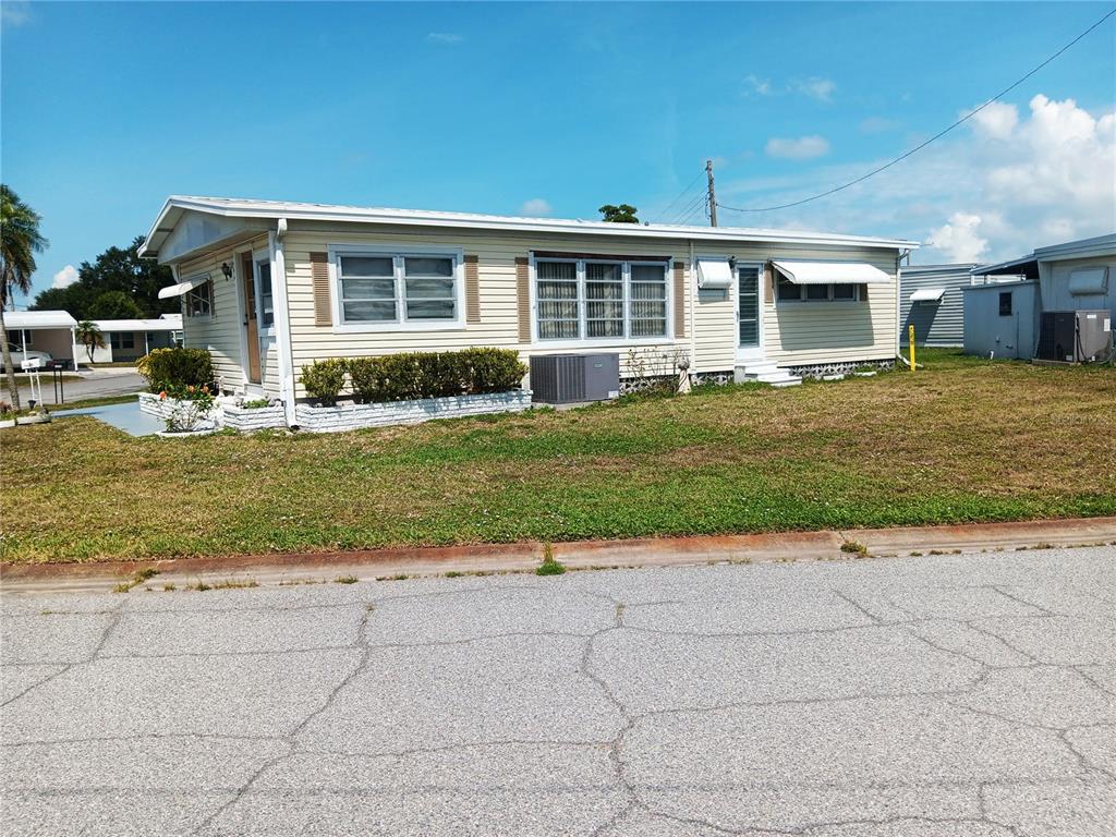 A single-story mobile home with light yellow siding sits on a grassy lot — 1781 OLYMPIA FIELDS STREET, SARASOTA, FL
