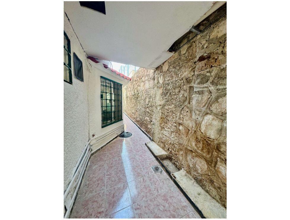A narrow outdoor walkway features tiled flooring, a white wall with windows, and a stone wall — . Calle Antilope No. 14 # 20, FL