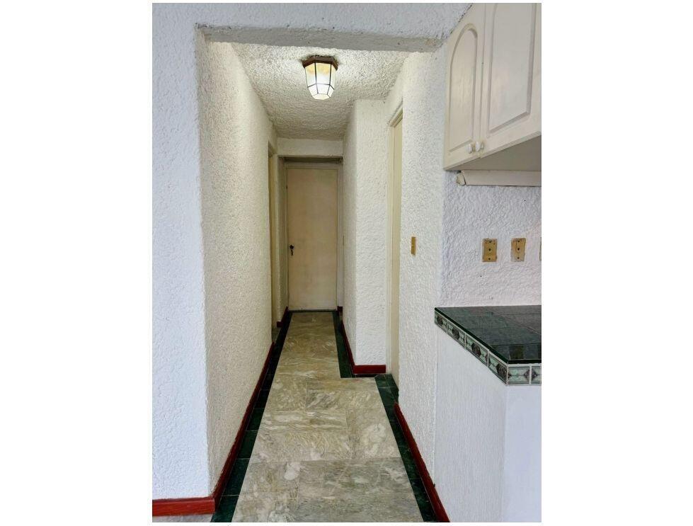 A narrow hallway features textured white walls, a light fixture, and green-accented tile flooring — . Calle Antilope No. 14 # 20, FL