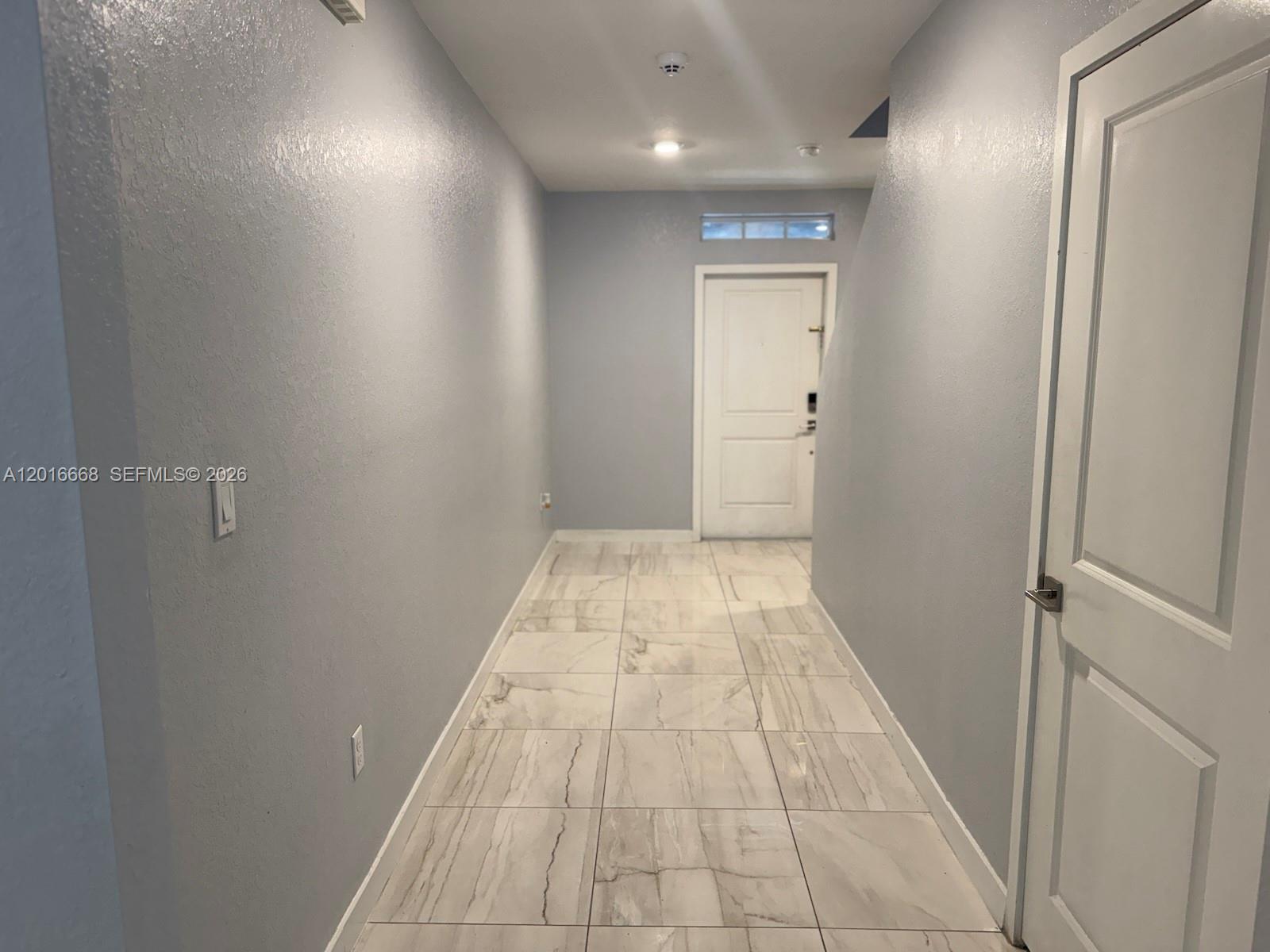 A hallway features gray walls, white trim, and light-colored marble-patterned tile flooring — 462 NE 6th Pl, Florida City FL 33034, FLORIDA CITY, FL