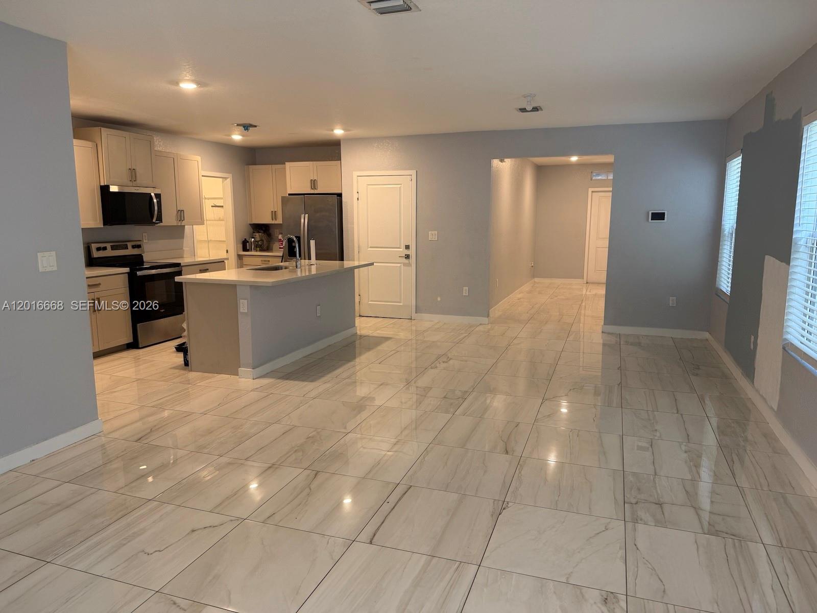 An open-concept kitchen and living area features light gray walls and white marble-look tile flooring — 462 NE 6th Pl, Florida City FL 33034, FLORIDA CITY, FL
