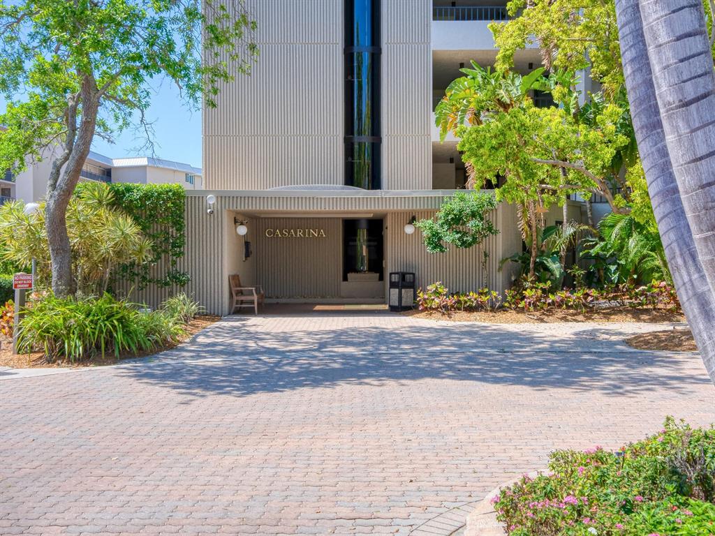 The exterior entrance of a multi-story building named Casarina features a paved driveway and landscaping — 5880 MIDNIGHT PASS ROAD UNIT 906, SARASOTA, FL