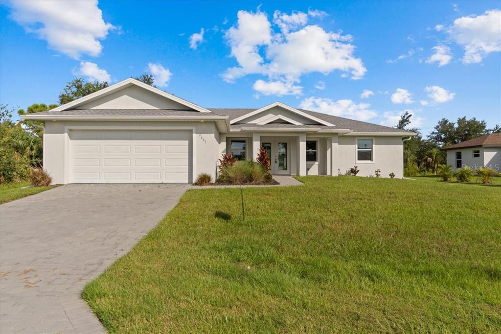 A single-story house with a white stucco exterior, a two-car garage, and a paved driveway — 9461 ATTICA CIRCLE, PORT CHARLOTTE, FL