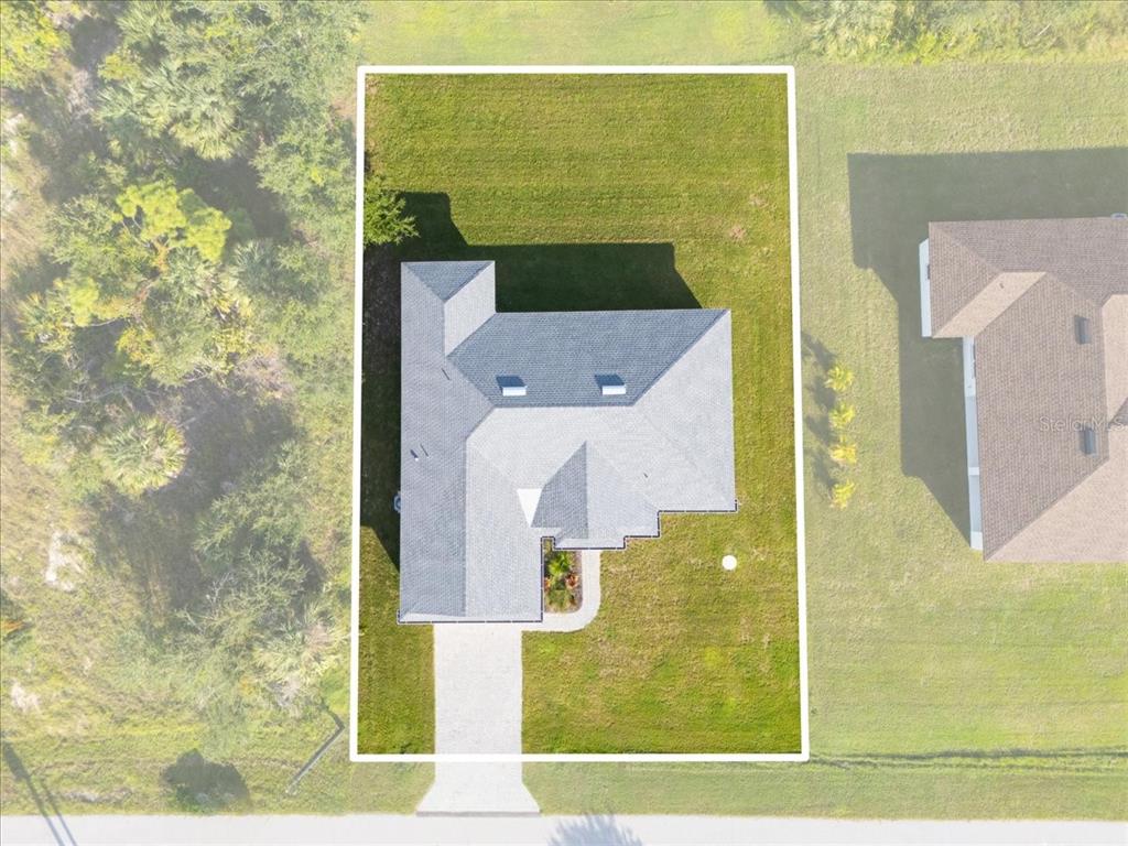 An aerial view shows a single-family home with a gray roof on a grassy lot — 9461 ATTICA CIRCLE, PORT CHARLOTTE, FL
