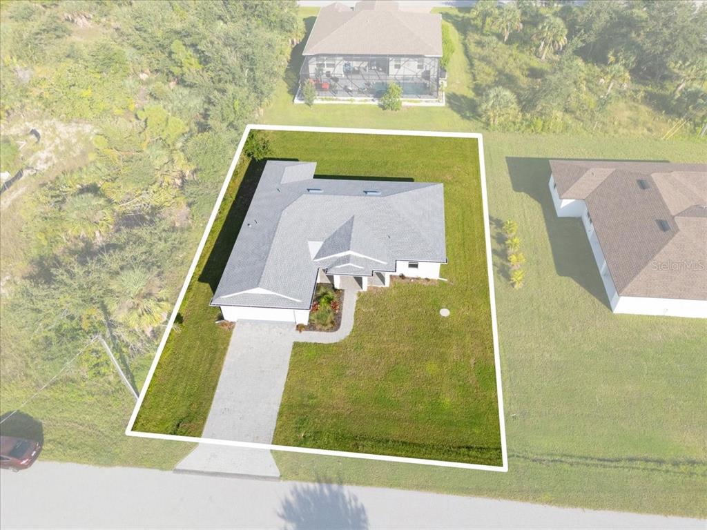 An aerial view shows a single-story house with a gray roof on a grassy lot — 9461 ATTICA CIRCLE, PORT CHARLOTTE, FL