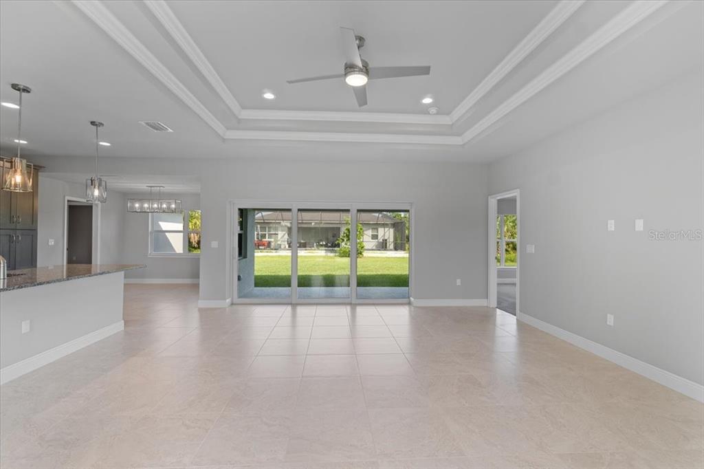A spacious living room with tile floors, a tray ceiling, and sliding glass doors to the backyard — 9461 ATTICA CIRCLE, PORT CHARLOTTE, FL