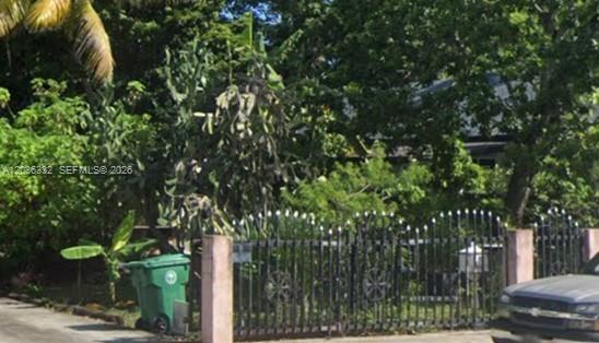 A black metal fence surrounds a yard with a large cactus and dense green trees — 821 NW 29th St, Miami FL 33127, MIAMI, FL