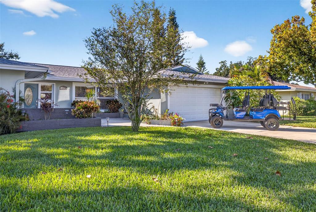 A single-story house with a white garage, a large lawn, and mature trees — 12620 138TH STREET N, LARGO, FL