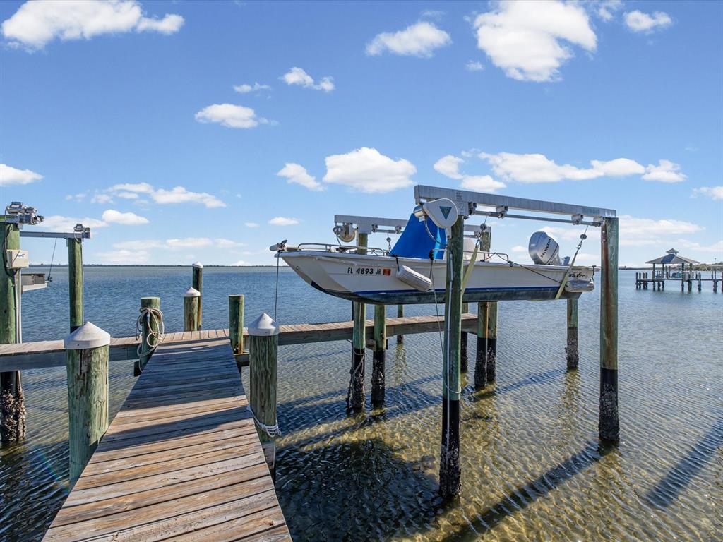 A boat is suspended on a lift above a wooden dock over the water — 413 S BAYSHORE BOULEVARD UNIT 4, SAFETY HARBOR, FL