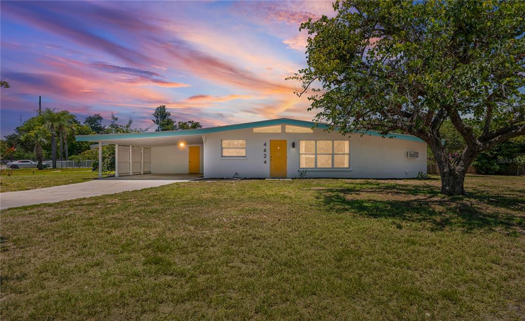 A single-story house with a carport, yellow front door, and a large tree in front — 4624 NAOMI RIDGE LANE, SARASOTA, FL