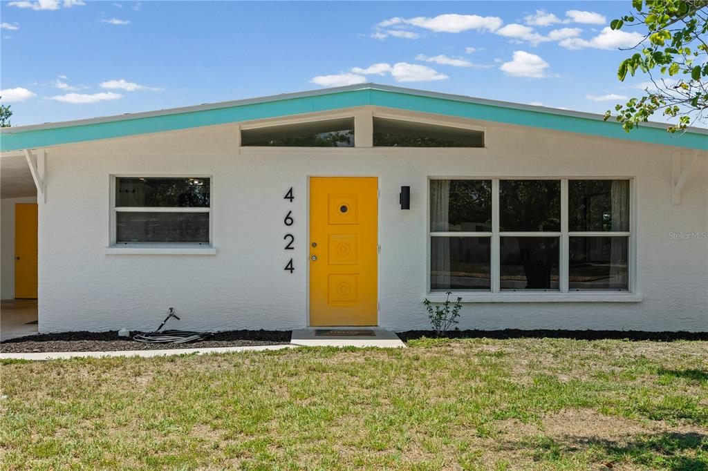 A white mid-century modern house features a bright yellow front door and turquoise roof trim — 4624 NAOMI RIDGE LANE, SARASOTA, FL