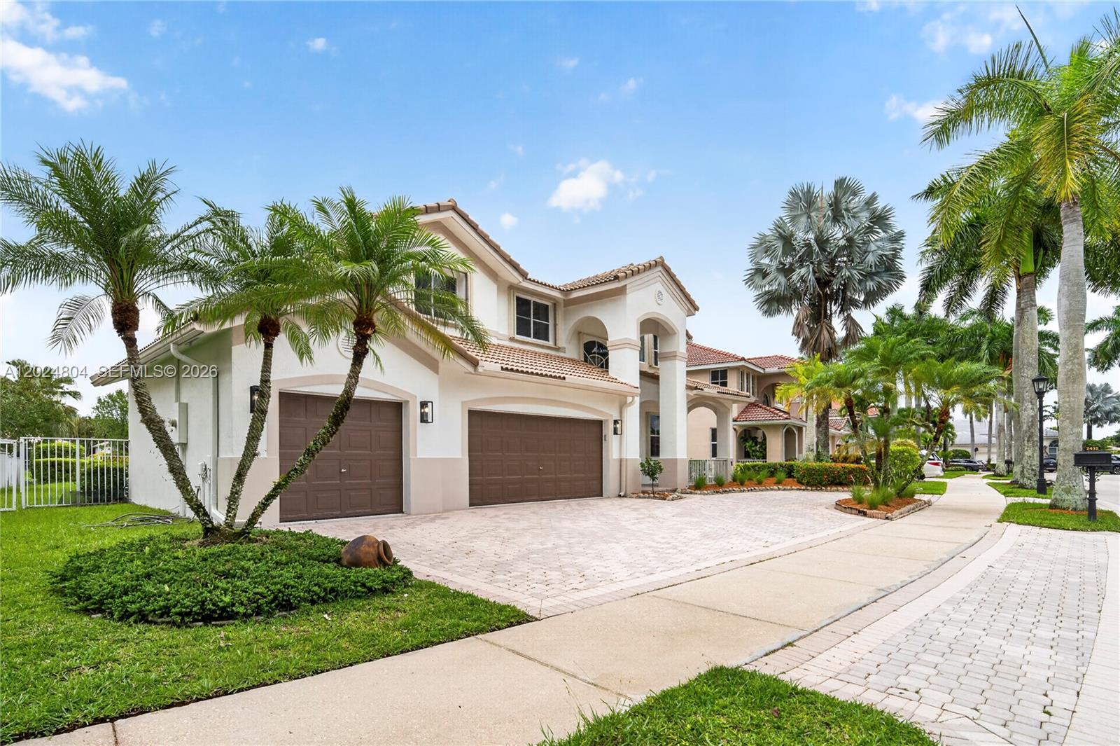A two-story house with a three-car garage, tile roof, and palm trees in the front — 2432 Deer Creek Rd, Weston FL 33327, WESTON, FL