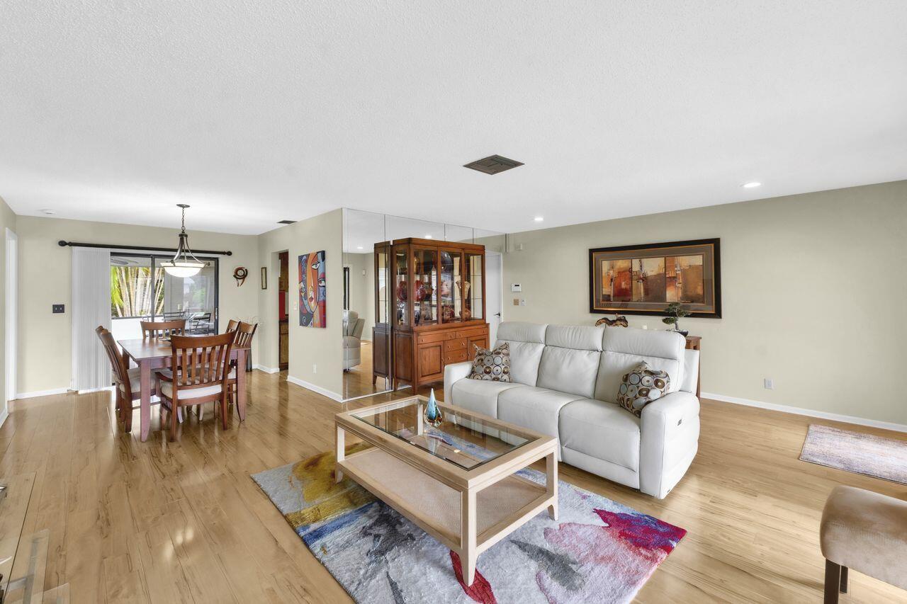 A living room with light wood floors, a white sofa, and a dining area nearby — 14765 Country Lane, Delray Beach FL 33484, DELRAY BEACH, FL