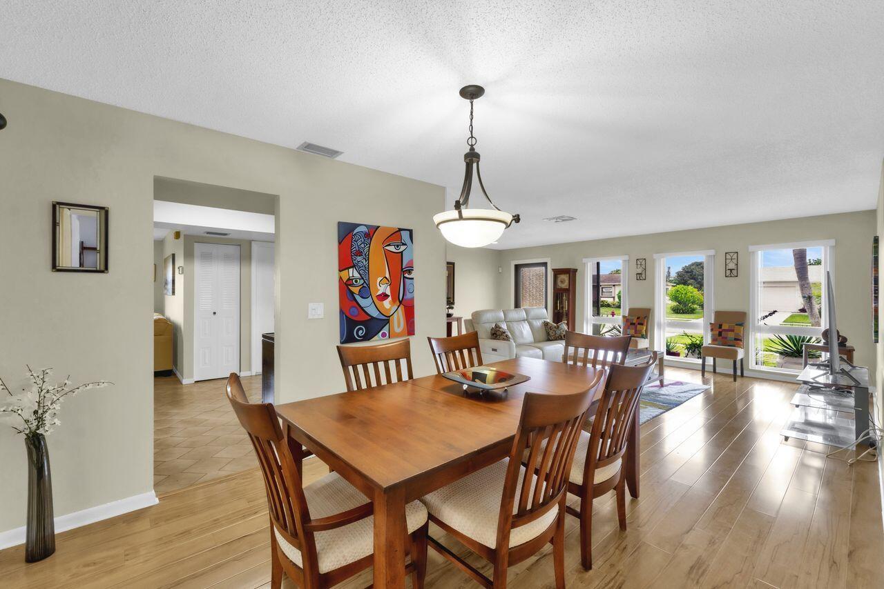 A dining area with a wooden table and chairs sits in front of a living room — 14765 Country Lane, Delray Beach FL 33484, DELRAY BEACH, FL