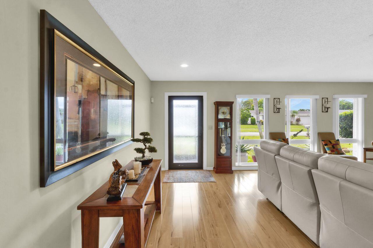 A living room features light wood flooring, a console table, a sofa, and a front door — 14765 Country Lane, Delray Beach FL 33484, DELRAY BEACH, FL