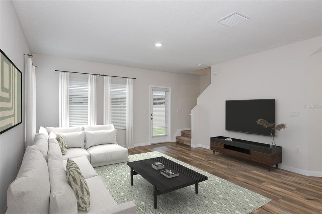 A living room features a white sectional sofa, a black coffee table, and a wall-mounted television — 9888 PELICAN COAST DRIVE, DADE CITY, FL