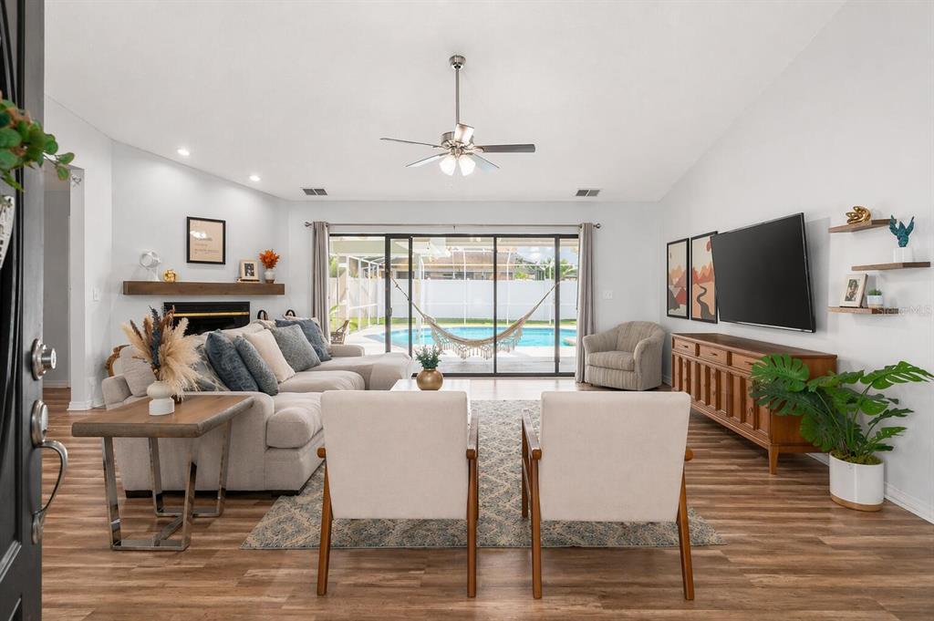 A living room with a sectional, two armchairs, a television, and a view of a pool — 7542 GUNSTOCK DRIVE, LAKELAND, FL