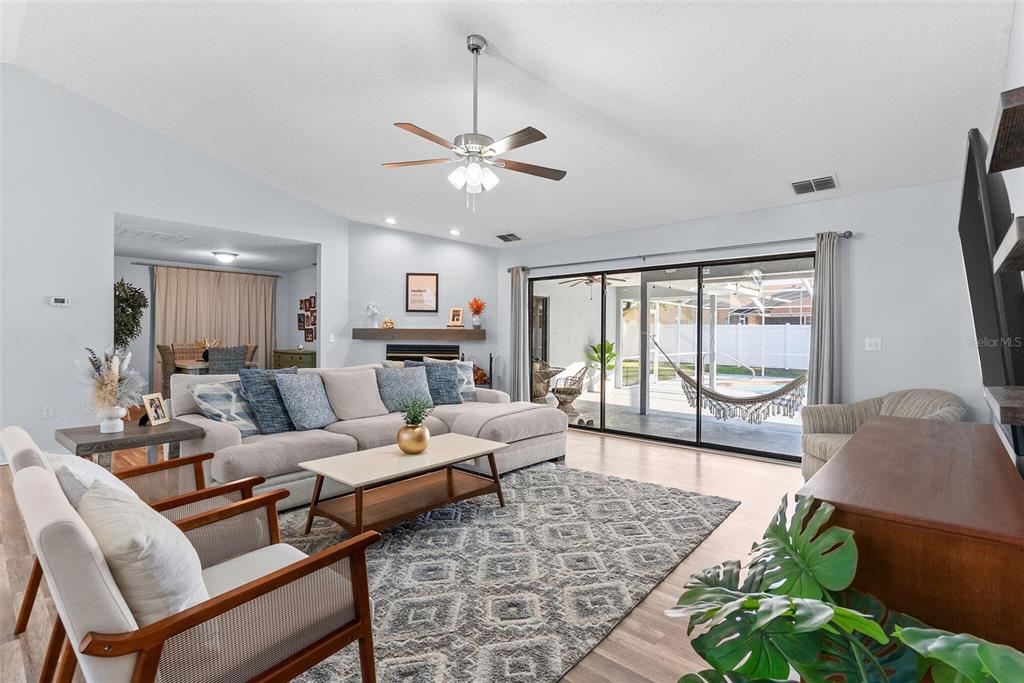A living room features a sectional sofa, area rug, fireplace, and sliding doors to a patio — 7542 GUNSTOCK DRIVE, LAKELAND, FL