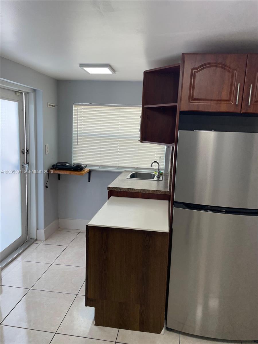 A small kitchen features a stainless steel refrigerator, a sink, and a portable electric burner — 3333 W 4th Ave # A, Hialeah FL 33012, HIALEAH, FL