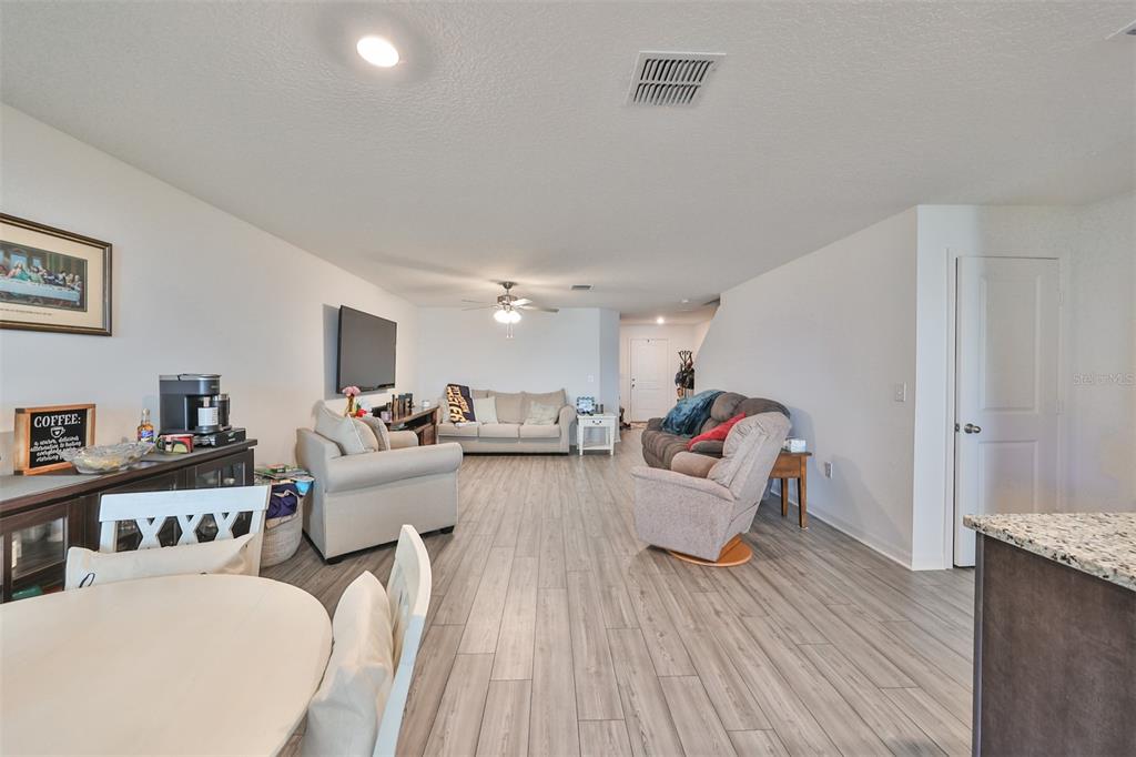 An open-concept living room features light wood-look flooring, neutral walls, and a dining area — 5311 NEW FRIENDSHIP PLACE, TAMPA, FL