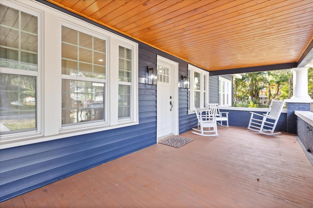 A covered front porch with blue siding, wood flooring, and white rocking chairs — 2001 SANFORD AVENUE, SANFORD, FL