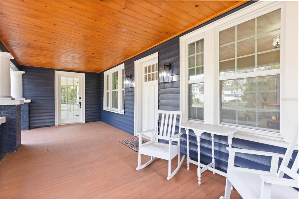 A covered porch features blue siding, a wood-paneled ceiling, and white rocking chairs — 2001 SANFORD AVENUE, SANFORD, FL