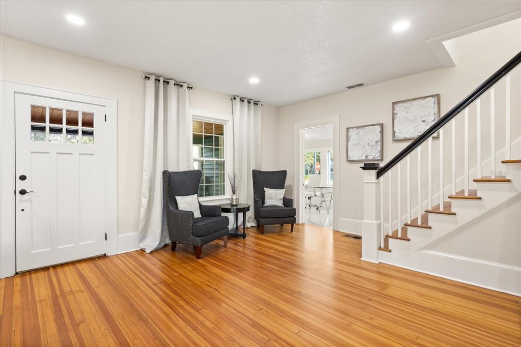 A bright entryway features hardwood floors, a staircase with a black railing, and two armchairs — 2001 SANFORD AVENUE, SANFORD, FL