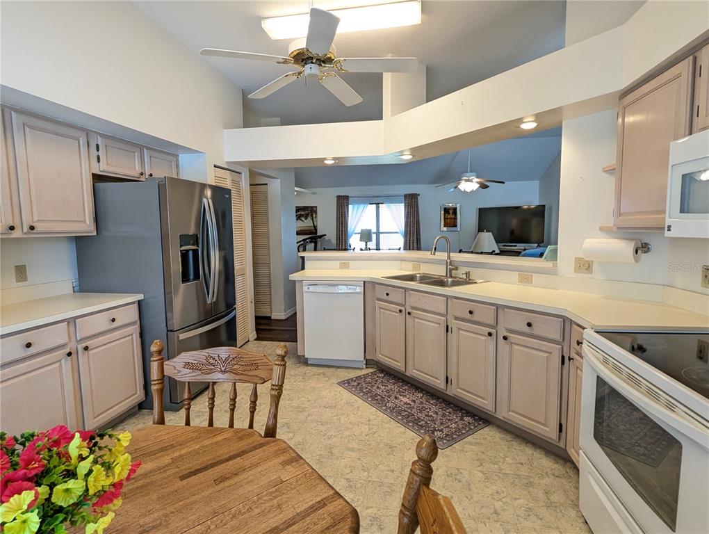 A kitchen features light wood cabinets, stainless steel appliances, and a breakfast table in the foreground — 4286 N MAE WEST WAY, BEVERLY HILLS, FL