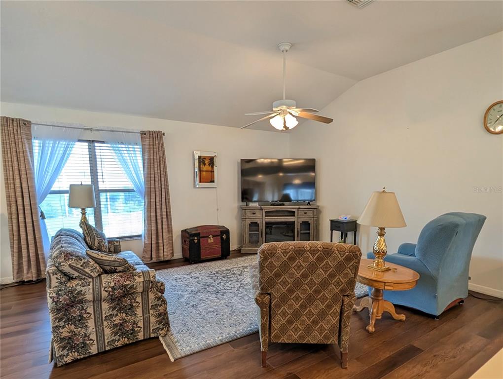 A living room features a floral sofa, patterned armchair, blue recliner, and wood-look flooring — 4286 N MAE WEST WAY, BEVERLY HILLS, FL