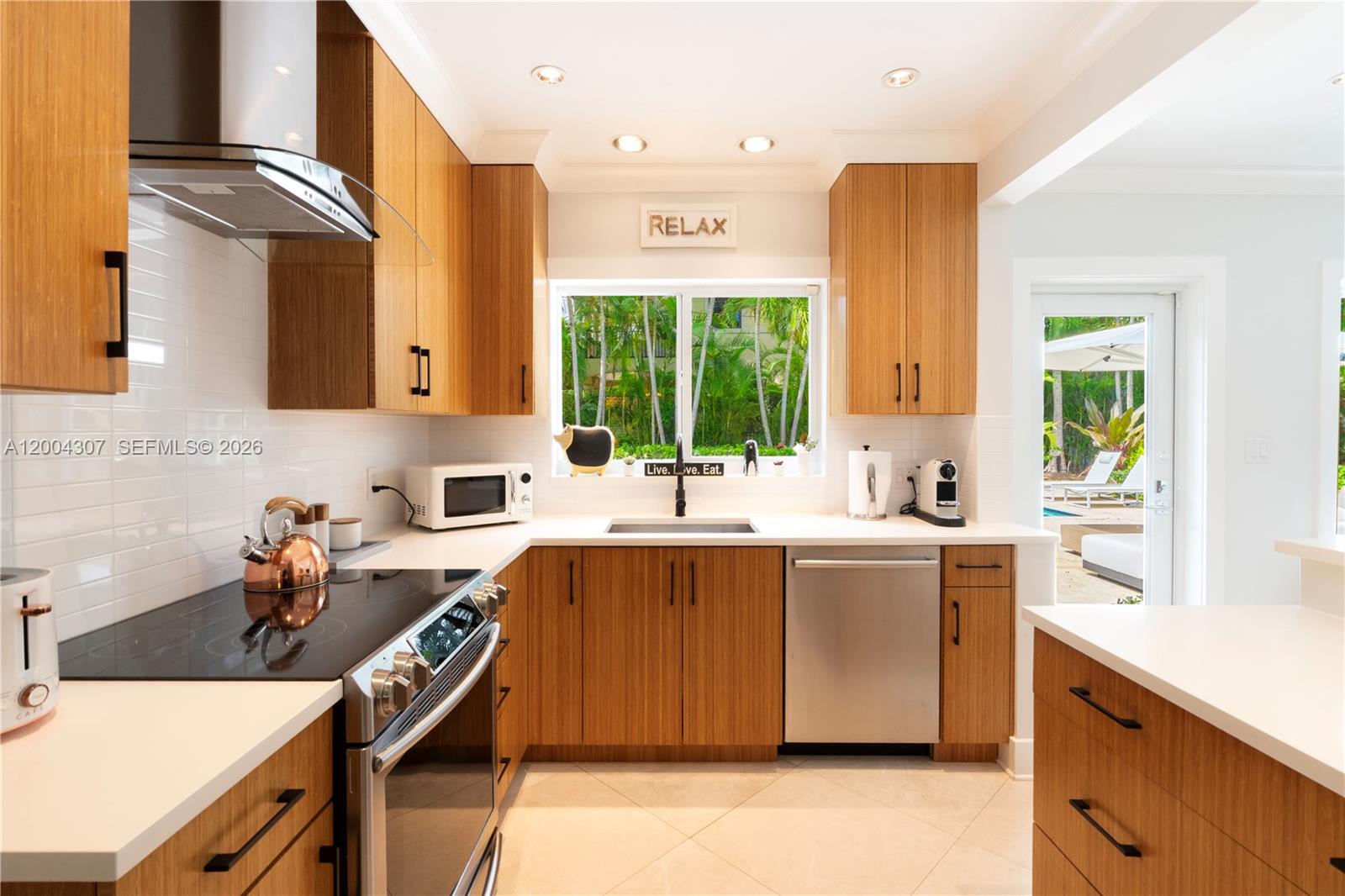 A kitchen features wood cabinets, white countertops, stainless steel appliances, and a window view — 1029 Mariposa Ave, Coral Gables FL 33146, CORAL GABLES, FL