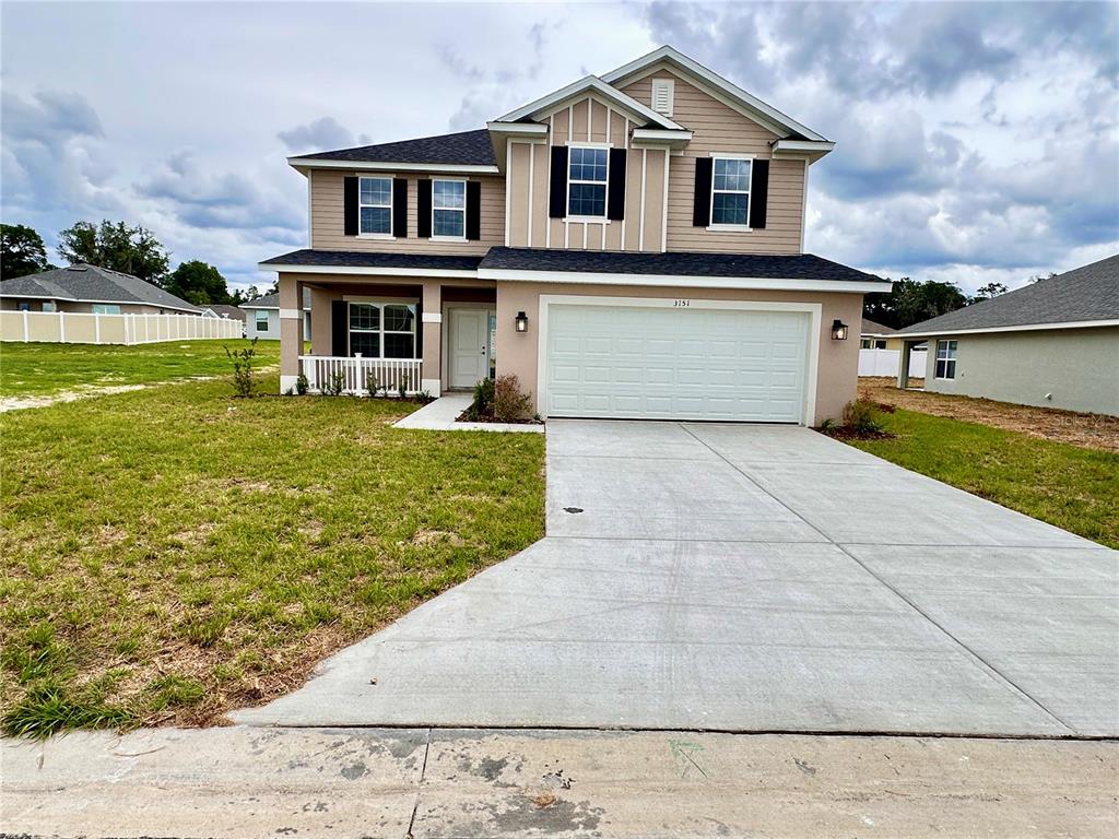 A two-story house with a tan exterior, a two-car garage, and a concrete driveway — 3151 NE 45TH AVENUE, OCALA, FL