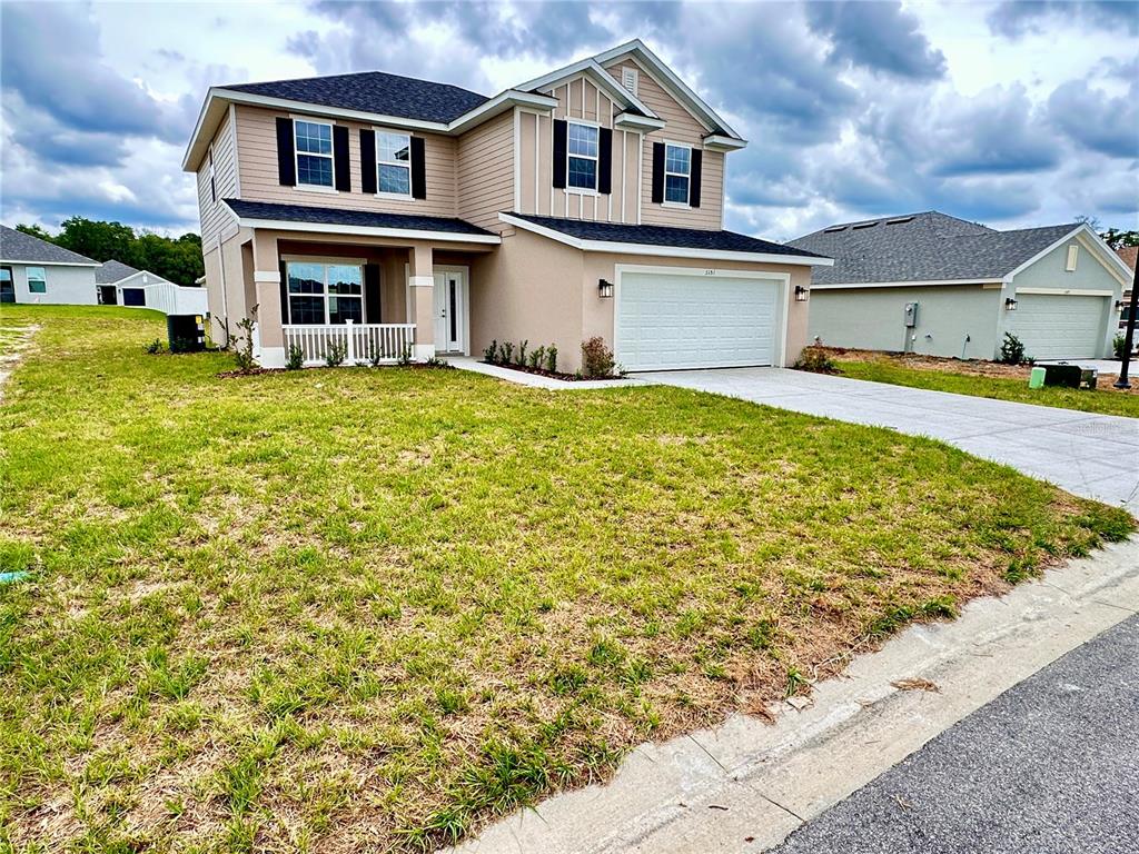 A two-story suburban house with beige siding, a white garage, and a front porch — 3151 NE 45TH AVENUE, OCALA, FL