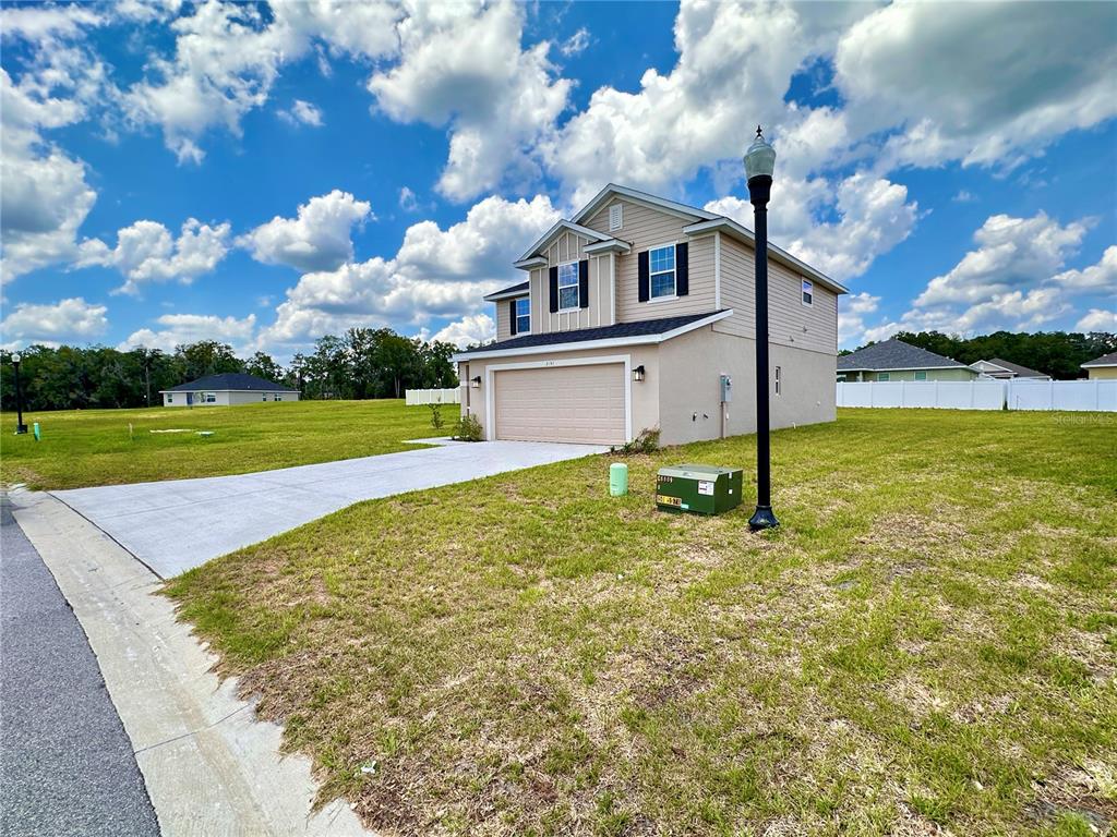 A two-story house with a tan exterior, a two-car garage, and a large grassy yard — 3151 NE 45TH AVENUE, OCALA, FL