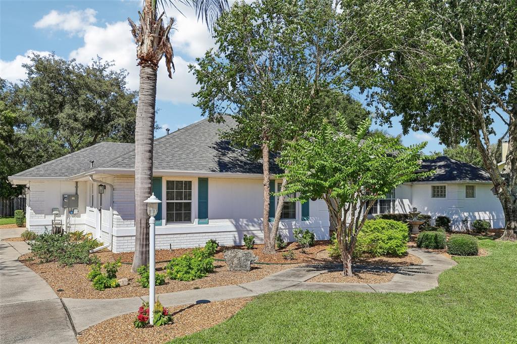 A white brick house with teal shutters and a palm tree in the front yard — 64 LAKE DIAMOND BOULEVARD, OCALA, FL