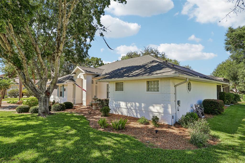 A white brick house with a dark shingled roof sits on a grassy lawn — 64 LAKE DIAMOND BOULEVARD, OCALA, FL