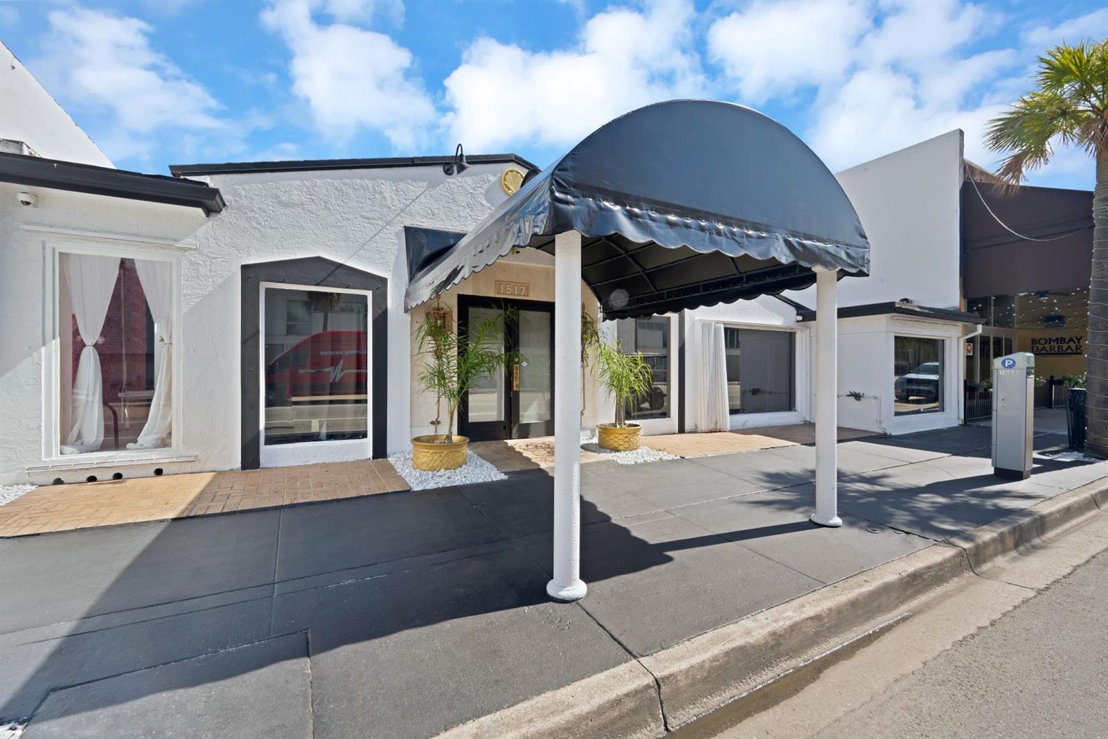 A white commercial building exterior features a black awning over the entrance and sidewalk — FORT LAUDERDALE, FL