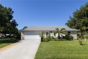 A single-story house with a white garage door, light siding, and a concrete driveway — 5740 36th Place, Vero Beach FL 32966, VERO BEACH, FL