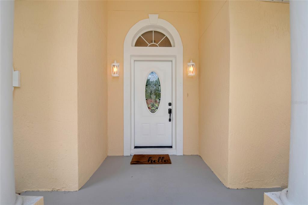 A white front door with an oval glass insert sits beneath an arched transom window — 2672 LAKE JACKSON CIRCLE, APOPKA, FL