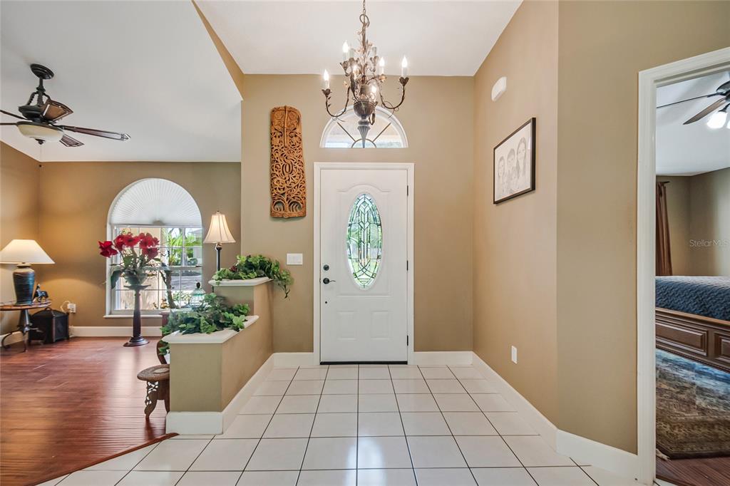 An entryway features a white front door, a chandelier, and tile flooring next to wood floors — 2672 LAKE JACKSON CIRCLE, APOPKA, FL