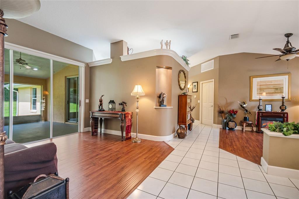 A living area features wood-look flooring, white tile, a curved wall niche, and sliding glass doors — 2672 LAKE JACKSON CIRCLE, APOPKA, FL