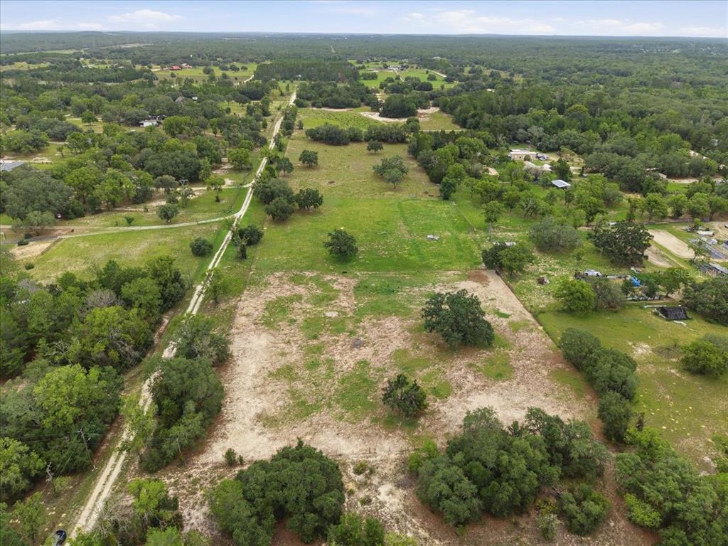 An aerial view shows a large, partially cleared grassy lot surrounded by trees and fencing — 7291 S WANDERLUST POINT, HOMOSASSA, FL