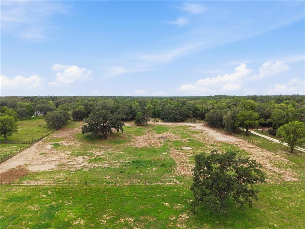 An aerial view shows a large, cleared grassy lot surrounded by mature trees — 7291 S WANDERLUST POINT, HOMOSASSA, FL