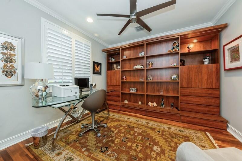 A home office features a glass desk, a large wooden wall unit, and a patterned rug — 310 E Mallory Circle, Delray Beach FL 33483, DELRAY BEACH, FL