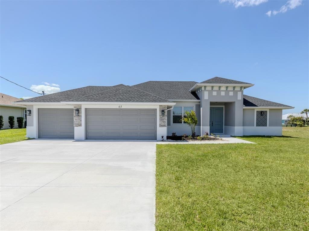 A single-story house with a gray stucco exterior, a three-car garage, and a concrete driveway — 65 FAIRWAY ROAD, ROTONDA WEST, FL