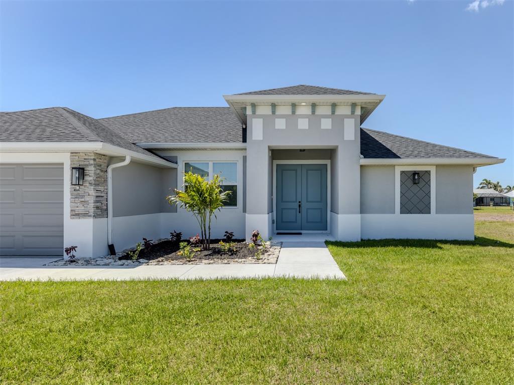 A single-story house features a gray exterior, double front doors, and a stone-accented garage — 65 FAIRWAY ROAD, ROTONDA WEST, FL
