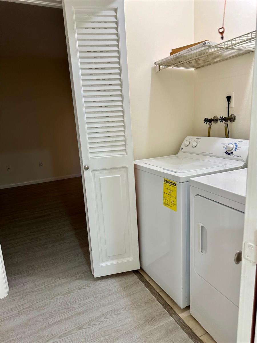 A laundry closet contains a white top-loading washer and dryer beneath a wire shelf — 8076 Ambach Way, Hypoluxo FL 33462, HYPOLUXO, FL