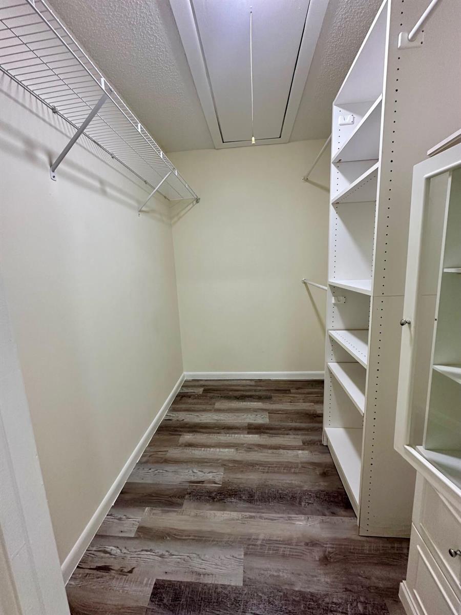 A walk-in closet features wire shelving, a white storage tower, and wood-look vinyl flooring — 8076 Ambach Way, Hypoluxo FL 33462, HYPOLUXO, FL
