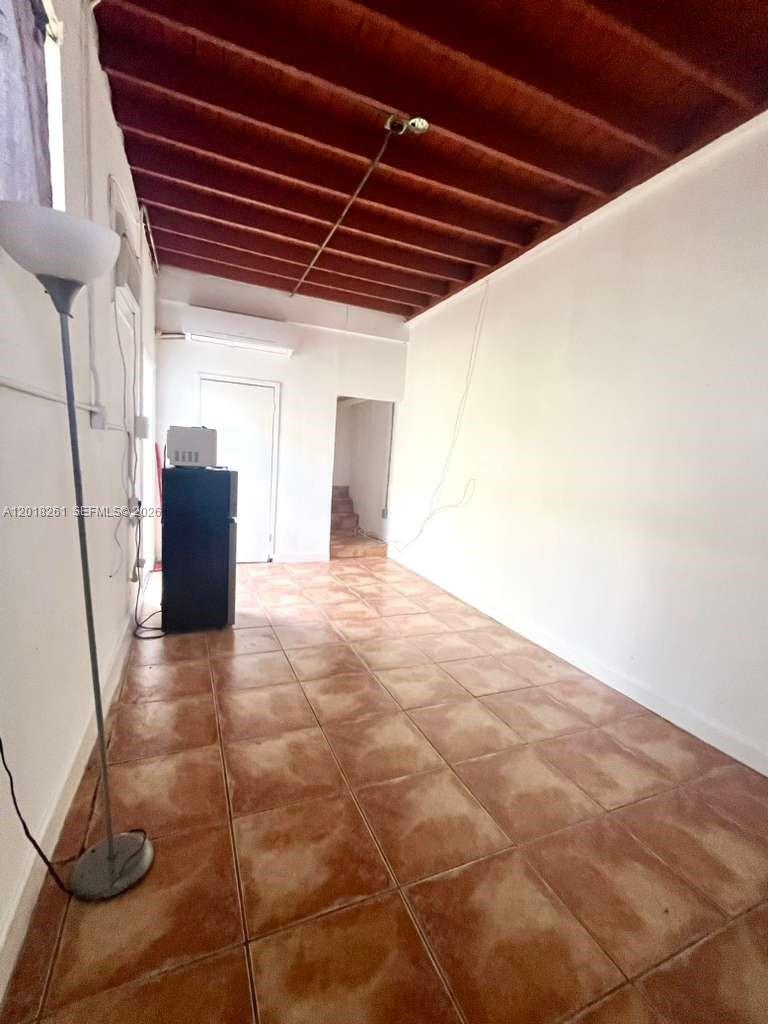 A narrow room features brown tile flooring, white walls, and an exposed wood beam ceiling — 1875 NE 177th St # 0, North Miami Beach FL 33162, NORTH MIAMI BEACH, FL