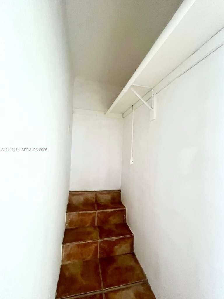 A small closet features a white shelf and brown tiled steps leading upward — 1875 NE 177th St # 0, North Miami Beach FL 33162, NORTH MIAMI BEACH, FL